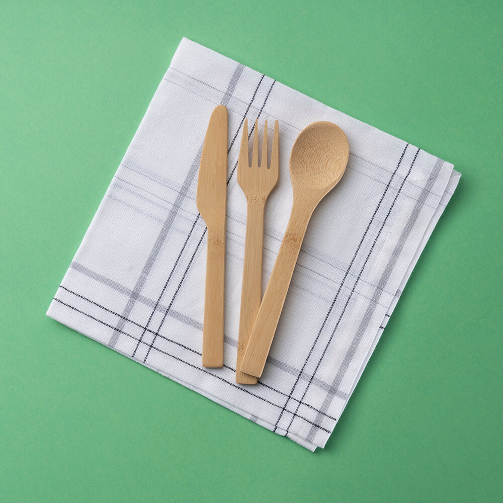 A Bamboo Cutlery Set: Spoon, Knife & Fork are laid out on a blue and white napkin.