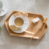 A Tiny Tong rests on a serving tray with a cup of tea. A scone and 2 sugar cubes are also on the tray.
