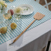 A Bamboo & Cork Fly Swatter rests on a blue and white tablecloth - bambu