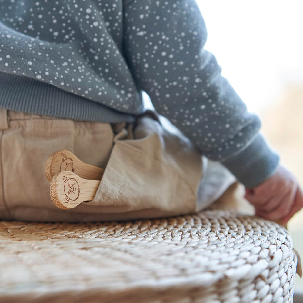 A set of  Organic Bamboo Kid's Fork & Spoon is shown in the pocket of a young child.