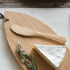 A 7" Bamboo Spreader is placed on a bamboo cutting board next to a wedge of brie cheese.