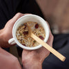 A bamboo trail spoon sits in a mug with oats and dried fruit - bambu