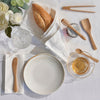 The bamboo tiny tools set of 5 are spread on a table ready for use. A jar of honey, loaf of bread, and cup of tea are part of the tablescape.