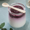 A Veneerware® 4" Tasting Spoon rests on top of a jar filled with yogurt and jam - bambu