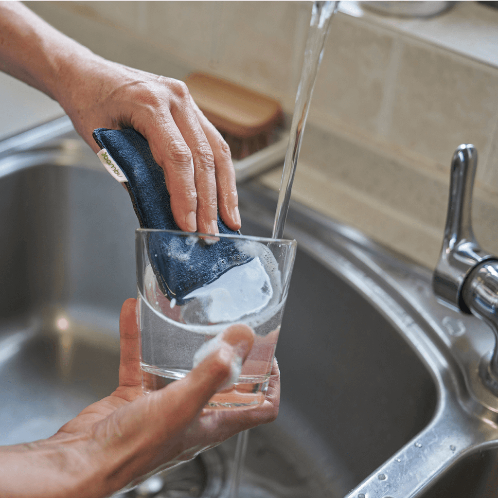 longlife sponge in teal is used to clean a drinking glass.