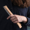 A person holds a cork fabric straw sleeve and glass straw.