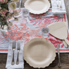 A table setting of Veneerware® Fancy Bamboo Plates is completed by white cloth napkins, silver flatware, and a pink and white floral tablecloth.