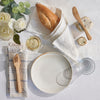 A tablescape featuring a 7" bamboo spreader, a set of bamboo cutlery, and a loaf of bread.