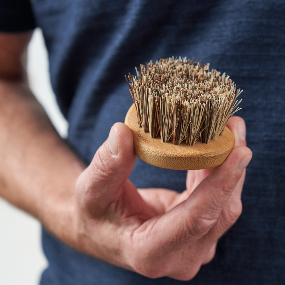 A person in a blue shirt holds a Pot & Pan Scrub Brush with the bristles up.