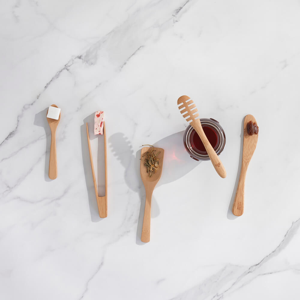 The bamboo tiny tools set of 5 is displayed on a marble countertop with small portions of food to show their potential uses.