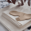 A pair of Veneerware® Bamboo Sporks are set atop a small stack of white napkins.