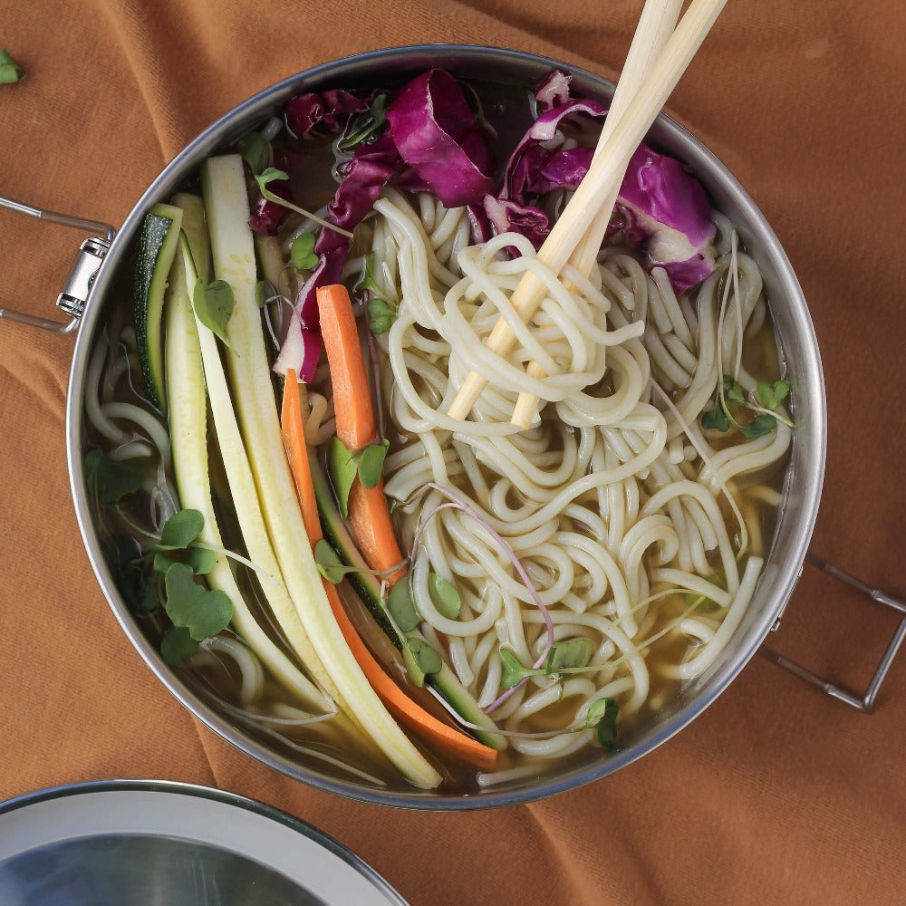 A meal of noodles and vegetables is ready to eat from an ECOlunchbox Stainless Bento Wet Box - Round 