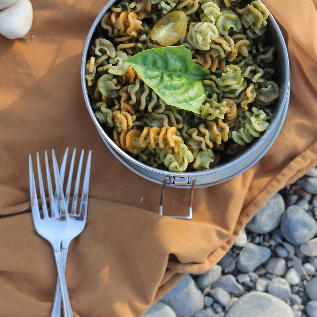 A meal of pasta with seasonings is ready to be eaten from an ECOlunchbox Stainless Bento Wet Box - Round