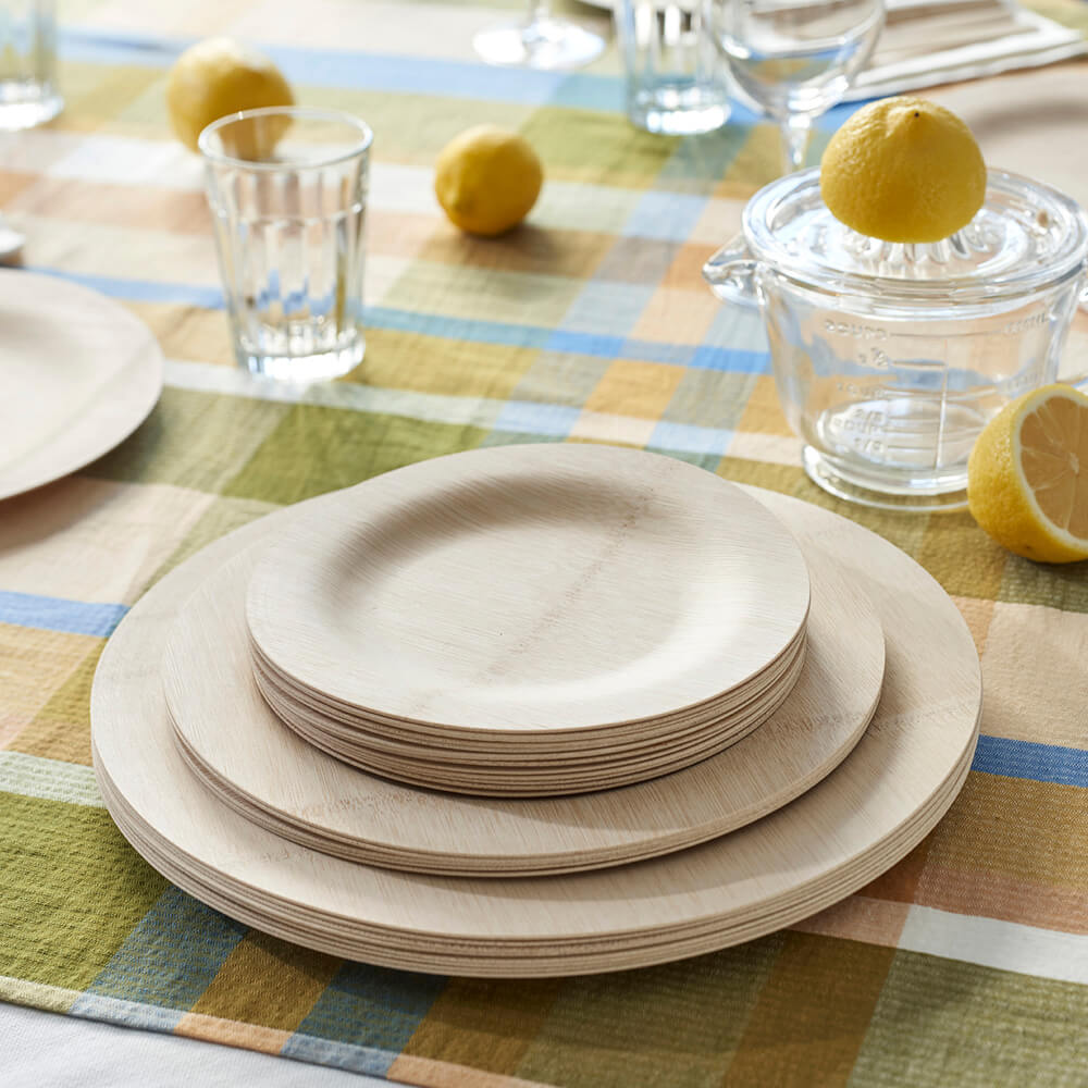 A stack of Round Veneerware plates is placed on a brightly colored tablecloth.