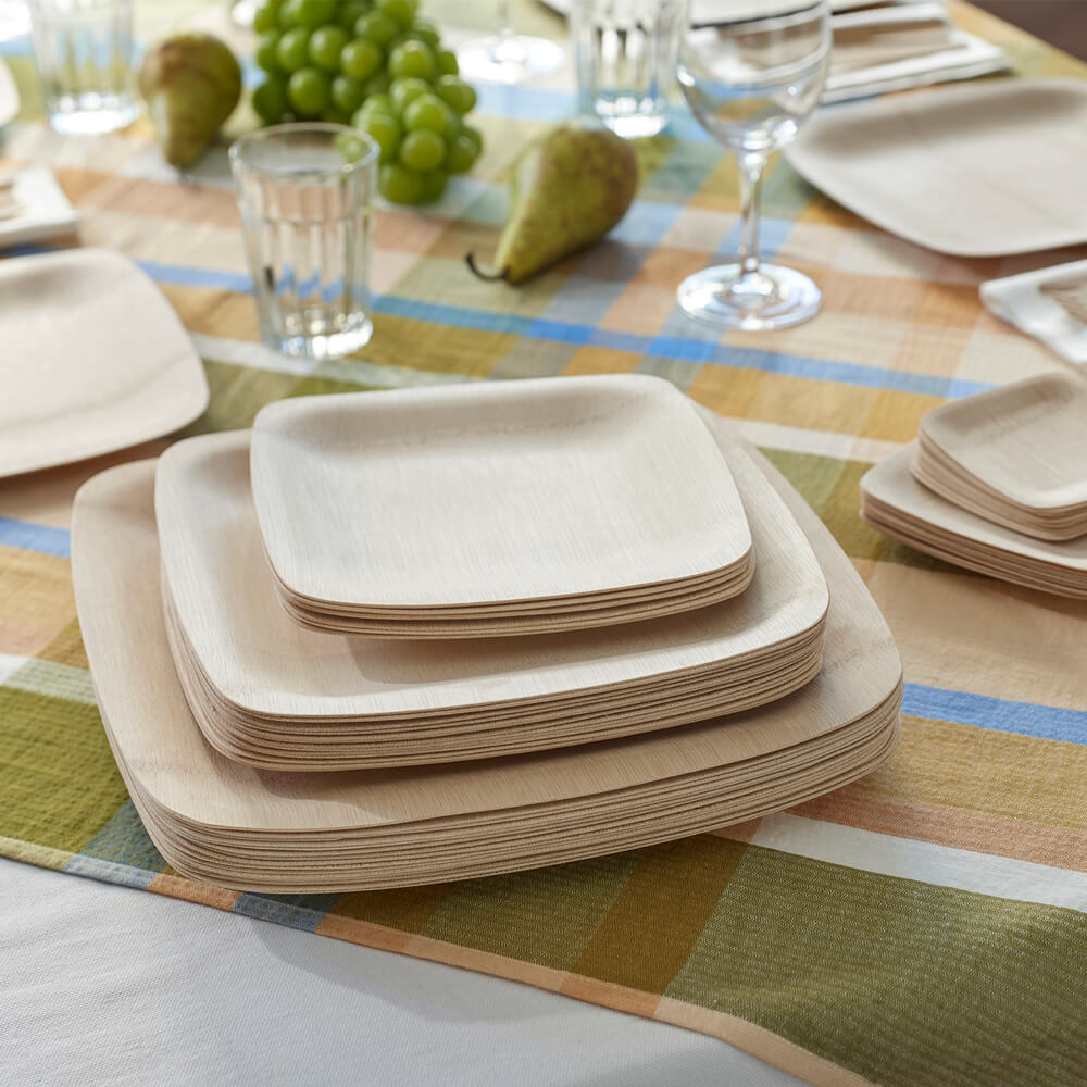 A stack of various sizes of Veneerware® Square Bamboo Plates is placed on a table. 