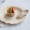 A Veneerware® Bamboo Spork is on a  dessert plate with a small fruit tart.
